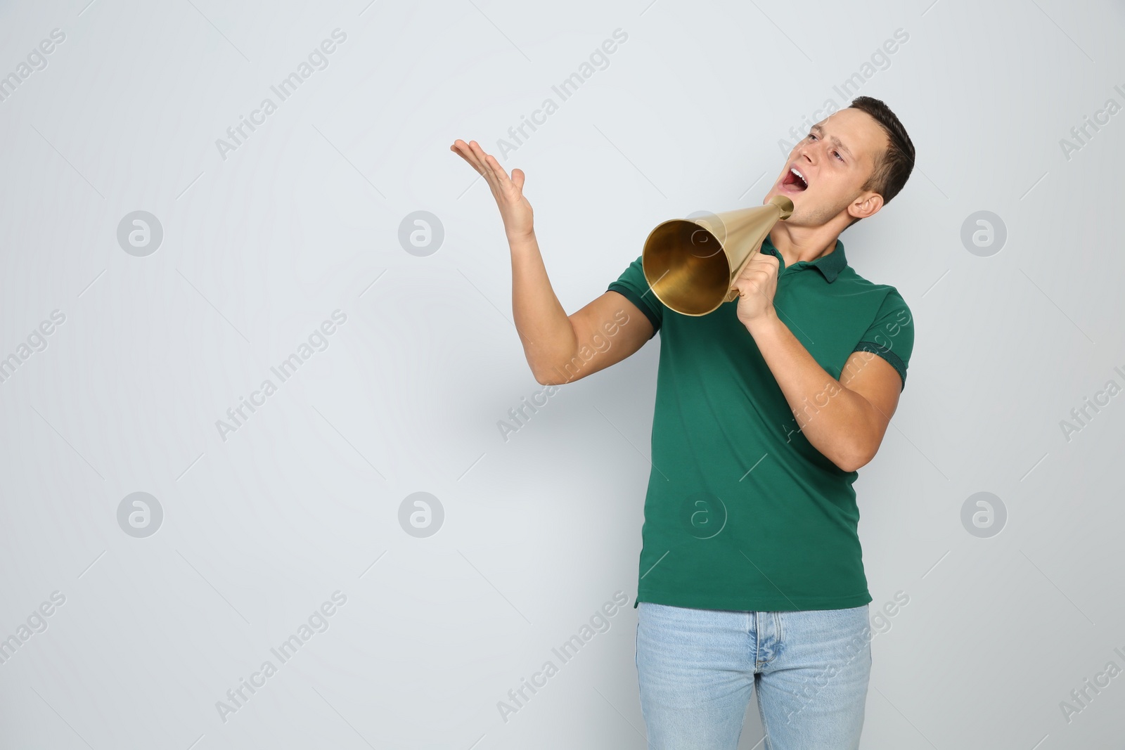 Photo of Emotional young man with megaphone on white background. Space for text