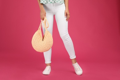 Photo of Young woman with stylish straw bag on pink background, closeup