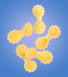 Image of Raw farfalline pasta falling on blue background