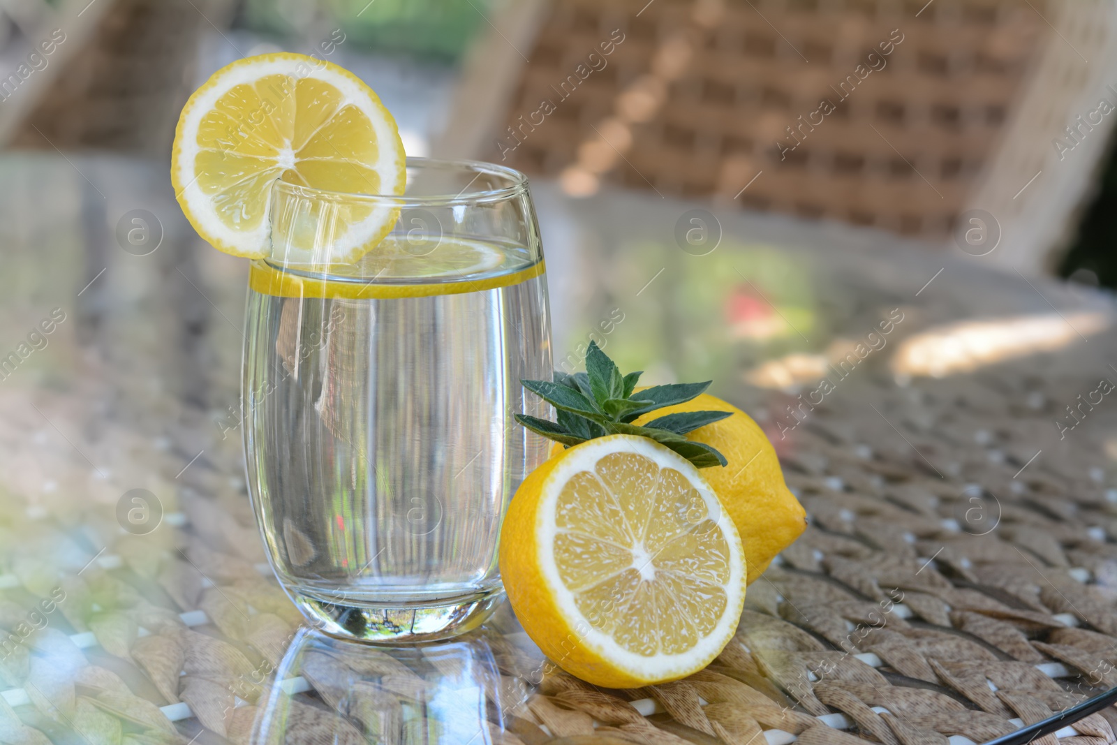 Photo of Refreshing water with lemon and mint on glass table in cafe
