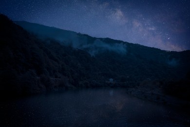 Image of Lake with reflection of starry sky near mountains. Amazing night landscape
