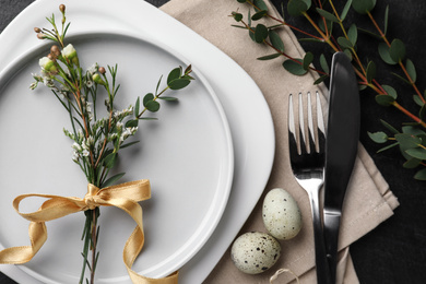 Photo of Festive Easter table setting with eggs and floral decoration on dark background, flat lay