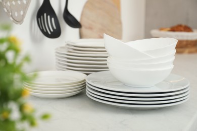 Clean plates and bowls on white marble countertop in kitchen