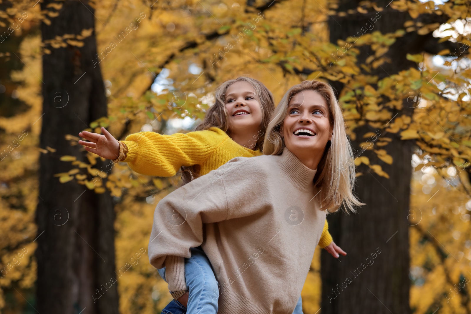 Photo of Happy mother with her daughter in autumn park, low angle view