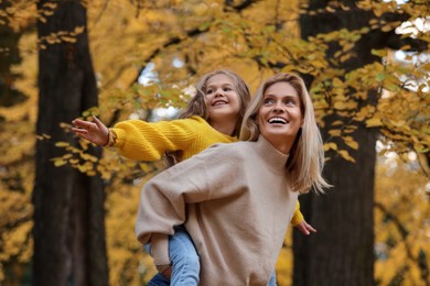 Photo of Happy mother with her daughter in autumn park, low angle view