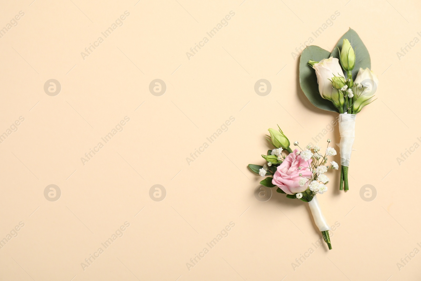 Photo of Wedding stuff. Stylish boutonnieres on beige background, top view. Space for text