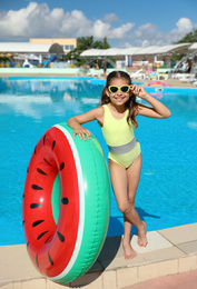 Photo of Little girl with inflatable ring near swimming pool. Summer vacation