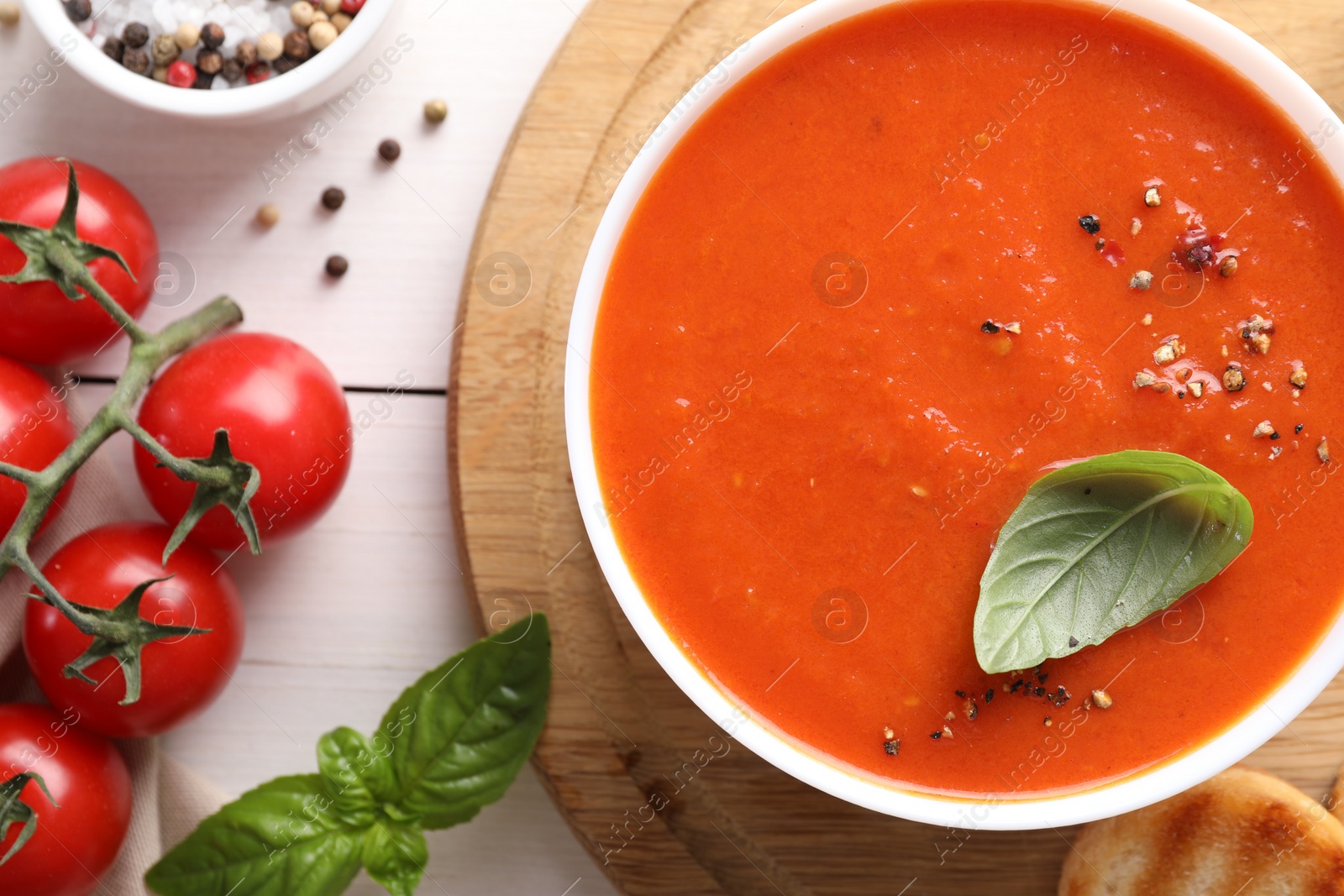 Photo of Delicious tomato soup served on white wooden table, flat lay