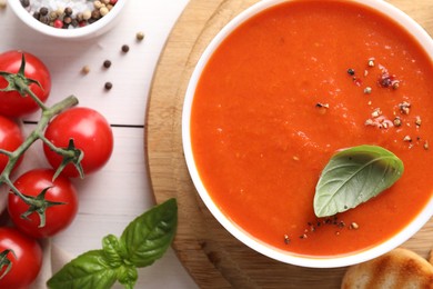 Photo of Delicious tomato soup served on white wooden table, flat lay