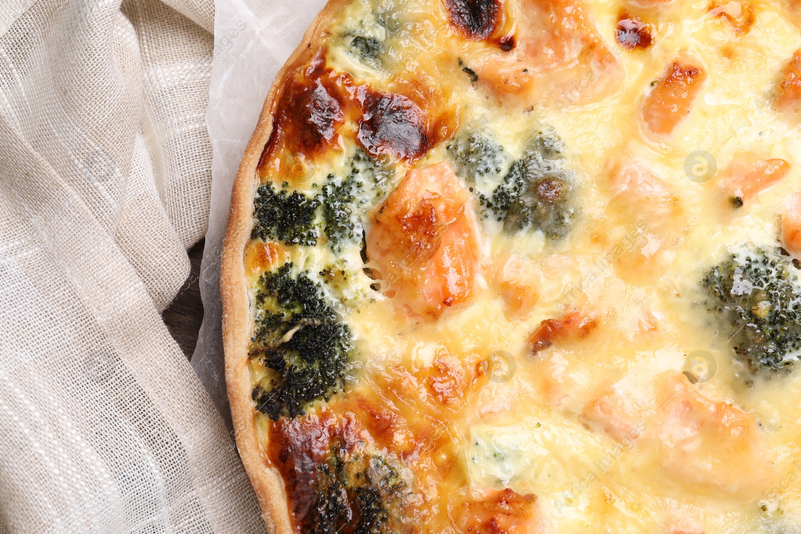 Photo of Delicious homemade quiche with salmon and broccoli on beige cloth, top view