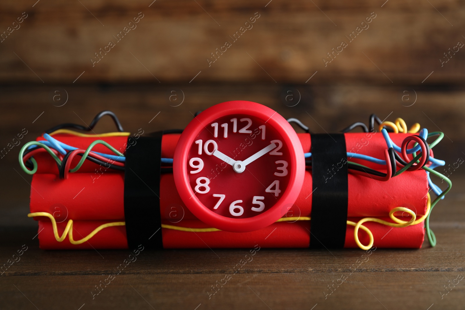 Photo of Dynamite time bomb on wooden table, closeup