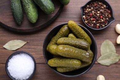 Photo of Bowl of pickled cucumbers and ingredients on wooden table, flat lay