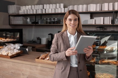 Photo of Happy business owner with tablet in bakery shop