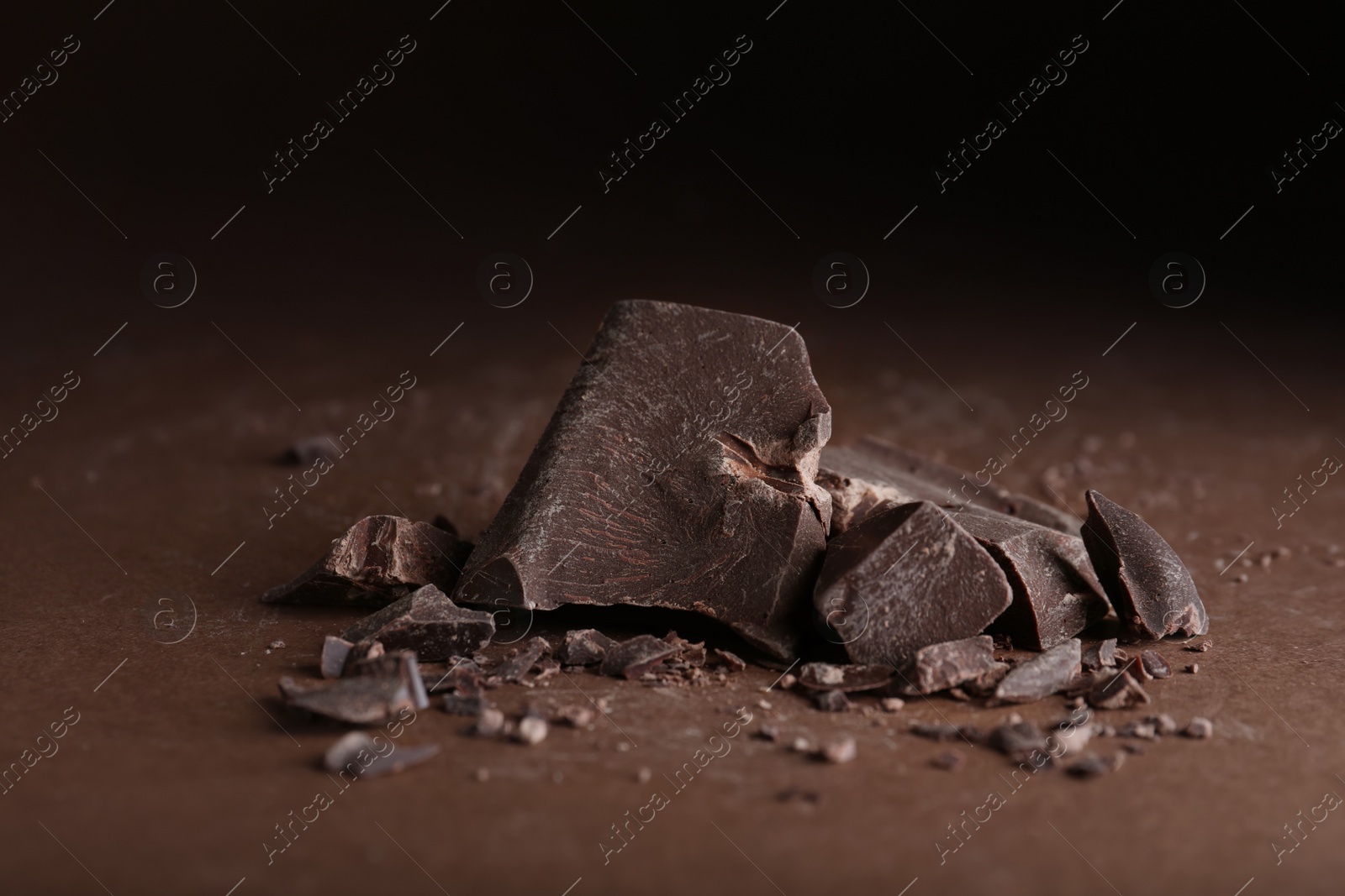 Photo of Pieces of dark chocolate on brown table