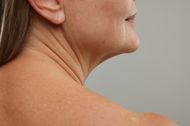 Mature woman with healthy skin on grey background, closeup