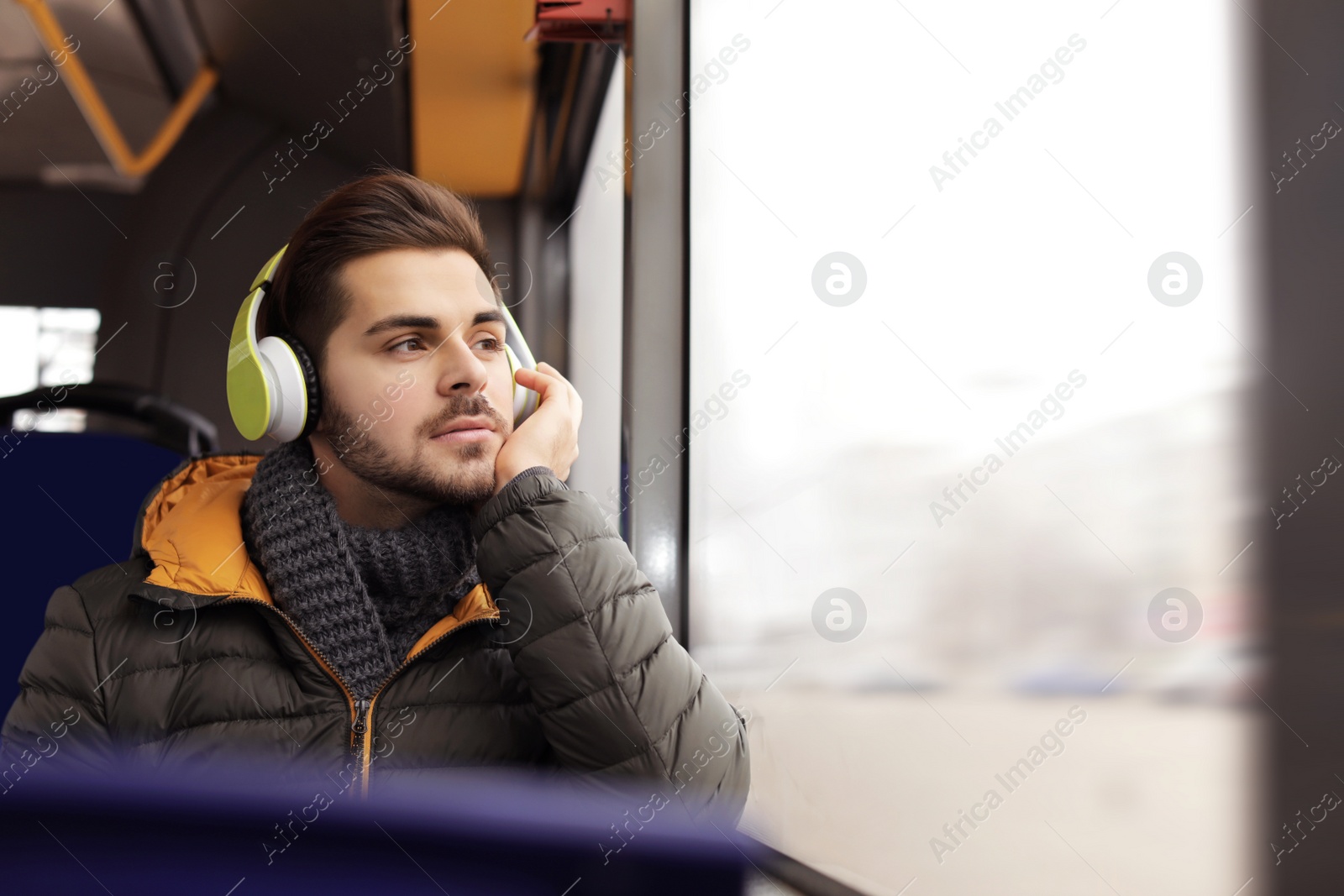 Photo of Young man listening to music with headphones in public transport