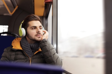 Photo of Young man listening to music with headphones in public transport