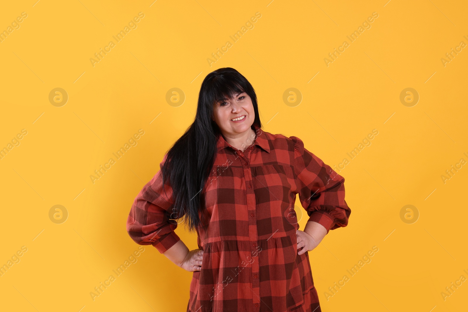 Photo of Beautiful overweight mature woman with charming smile on yellow background