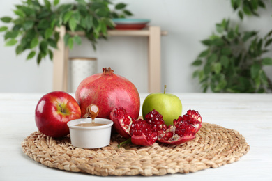 Photo of Honey, apples and pomegranate on white wooden table. Rosh Hashanah holiday