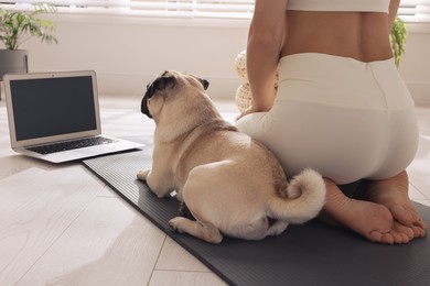 Photo of Woman with dog watching online yoga class at home, closeup