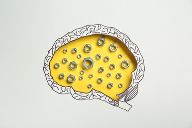 Analytical thinking. Nuts on yellow background, top view through paper with brain shaped hole and drawing