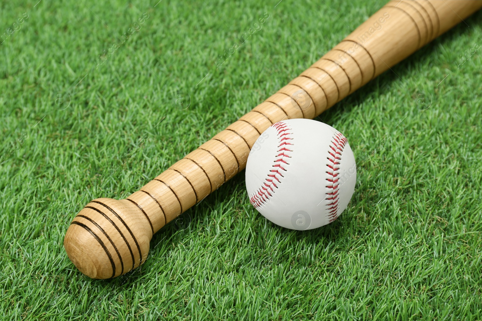 Photo of Wooden baseball bat and ball on green grass. Sports equipment