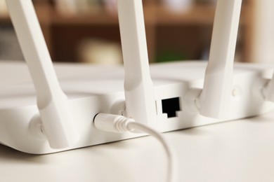 Photo of New Wi-Fi router on white table indoors, closeup