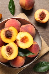 Photo of Delicious juicy peaches and leaves on wooden table, flat lay