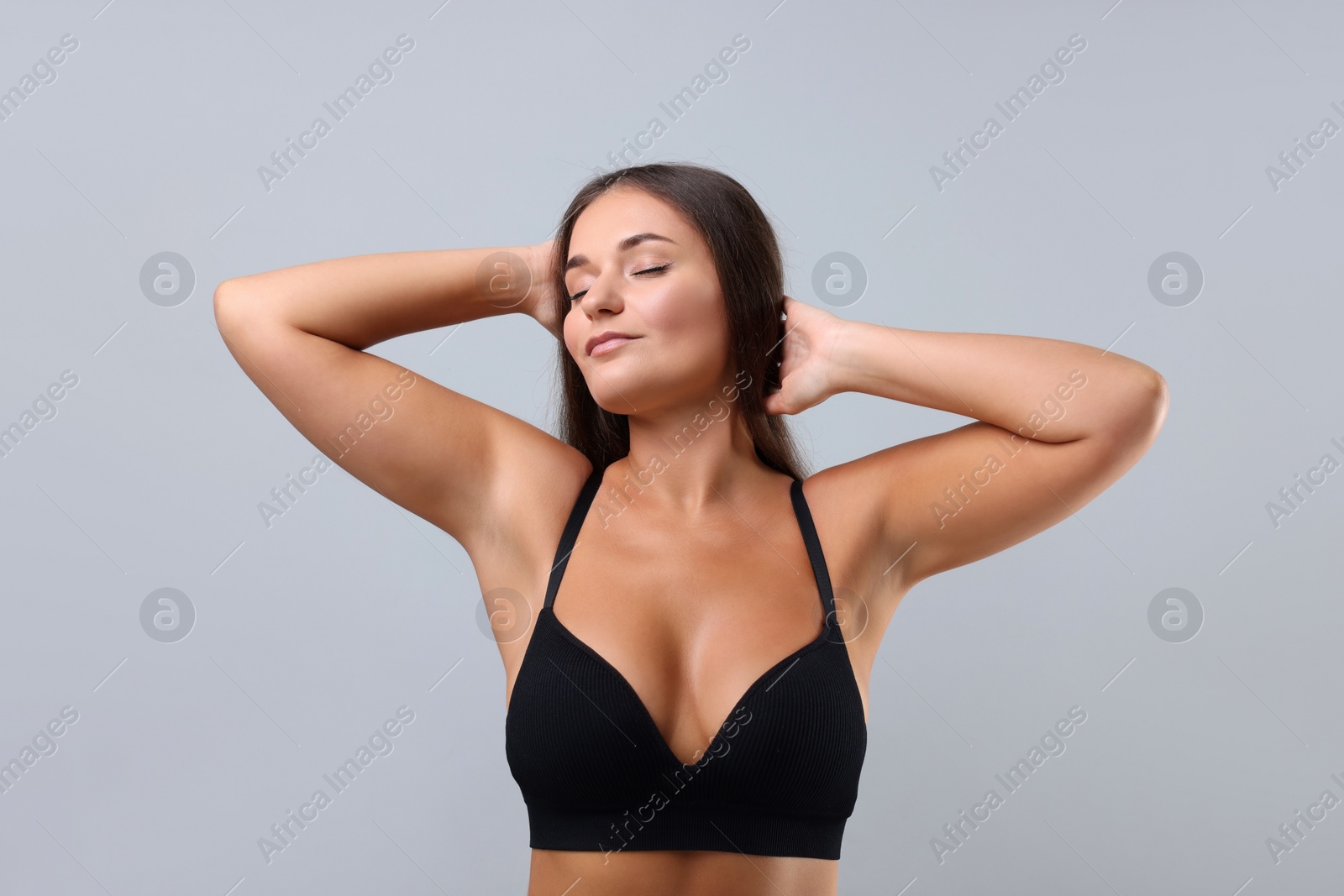 Photo of Portrait of young woman with beautiful breast on light grey background