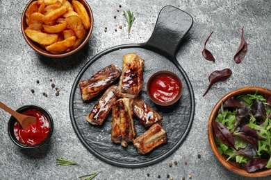 Photo of Delicious ribs on grey table, flat lay