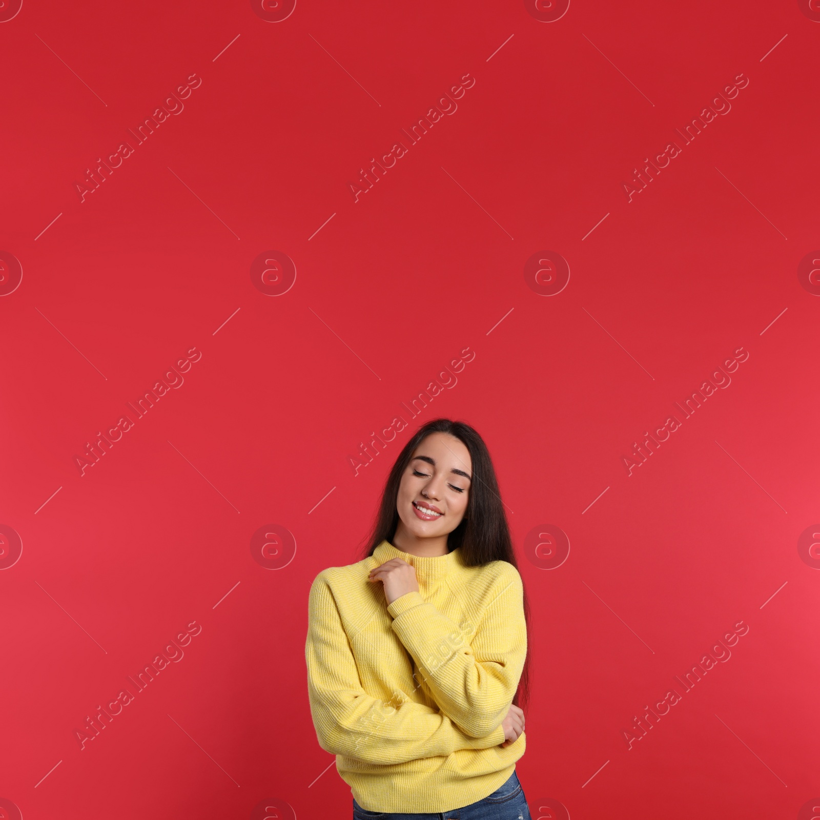 Photo of Beautiful young woman wearing yellow warm sweater on red background