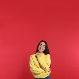 Photo of Beautiful young woman wearing yellow warm sweater on red background
