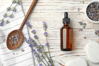 Photo of Flat lay composition with natural lavender essential oil on wooden table