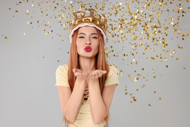 Photo of Beautiful young woman with inflatable crown blowing kiss on light grey background