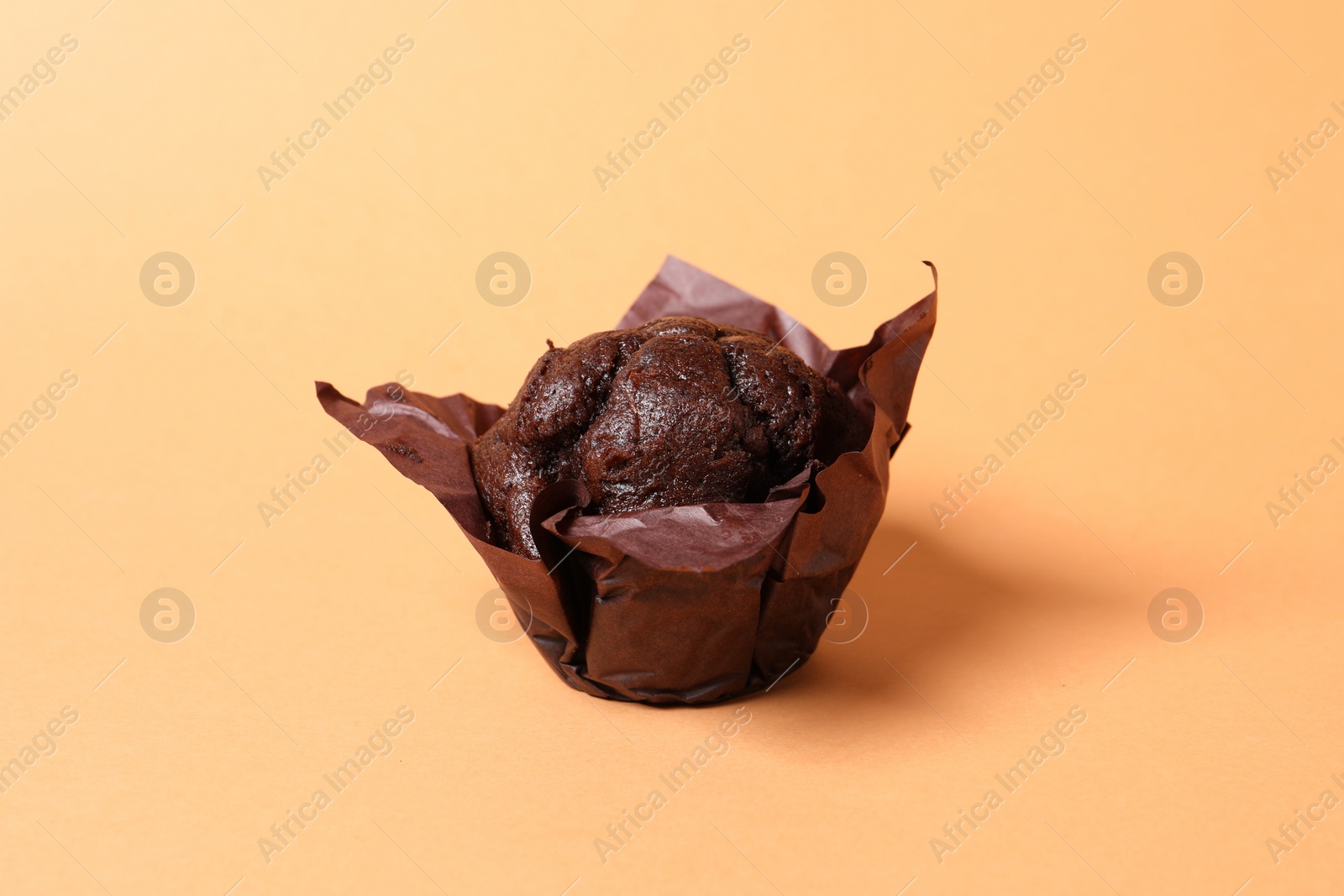 Photo of One tasty chocolate muffin on pale orange background