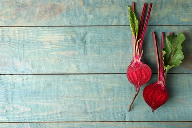 Halves of raw beet on blue wooden table, flat lay. Space for text