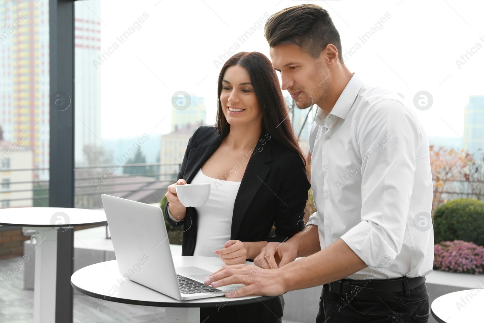 Photo of Business people with laptop in outdoor cafe. Corporate blog