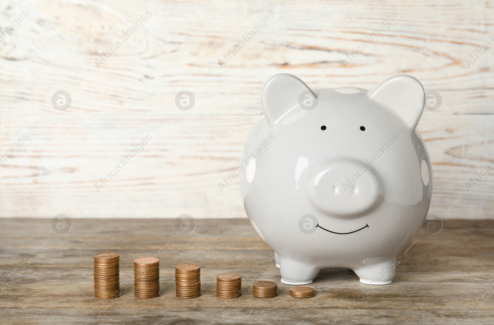 Photo of Piggy bank and different height coin stacks on table against light background. Space for text