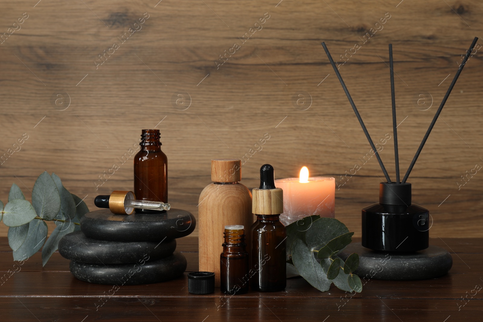 Photo of Aromatherapy products and burning candle on wooden table