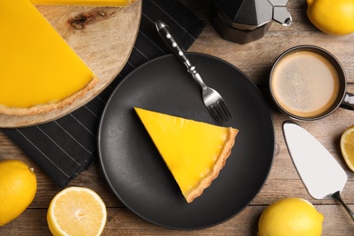 Photo of Delicious homemade lemon pie, fruits and coffee on wooden table, flat lay