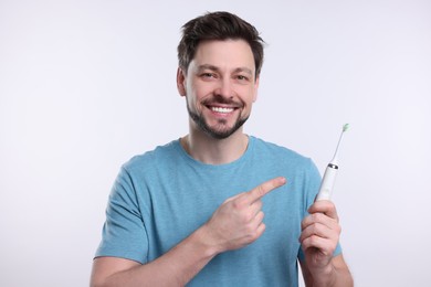 Happy man holding electric toothbrush on white background