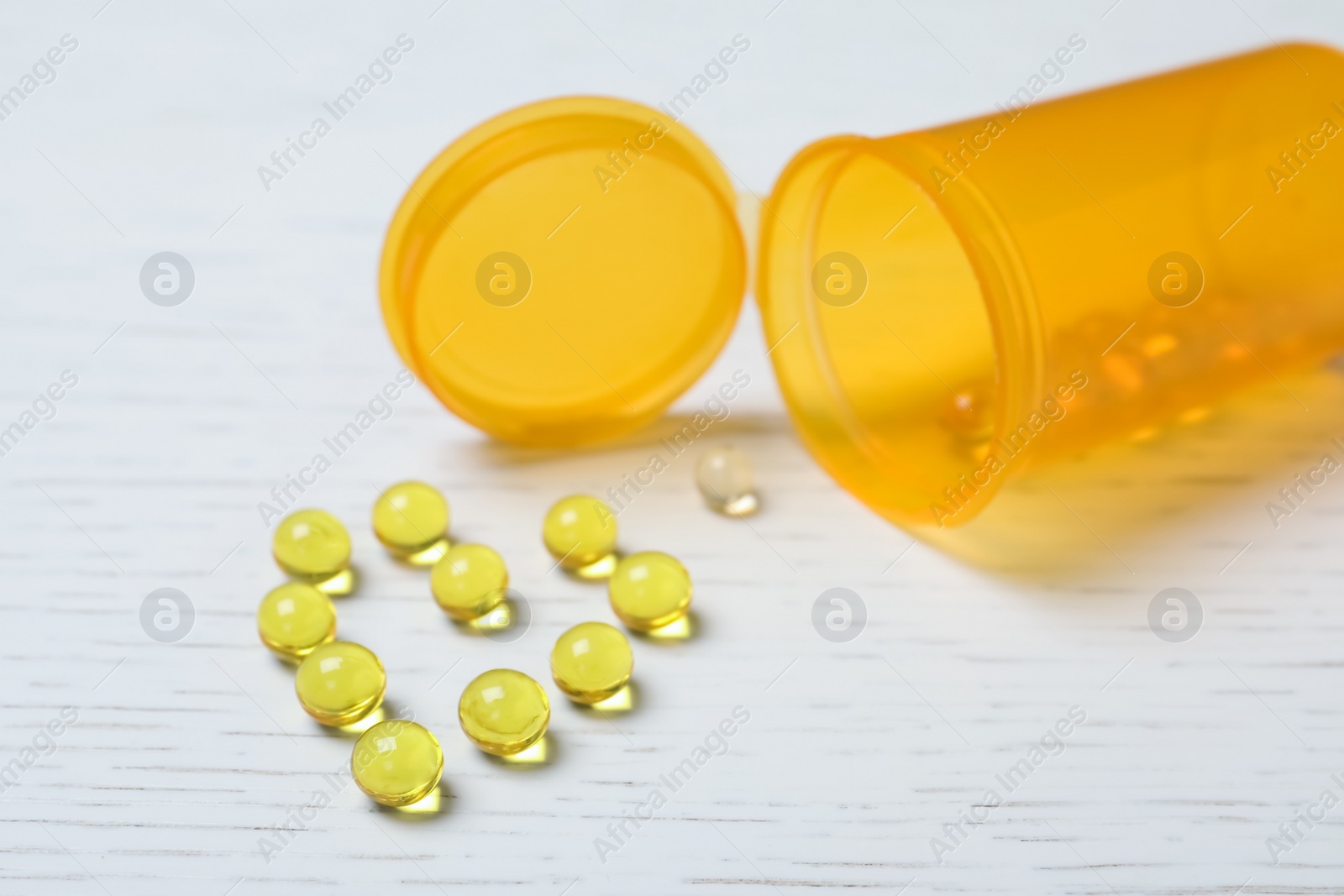 Photo of Heart made of pills and container on wooden background. Cardiology concept