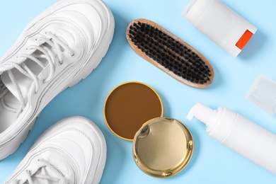 Photo of Flat lay composition with stylish footwear and shoe care accessories on light blue background