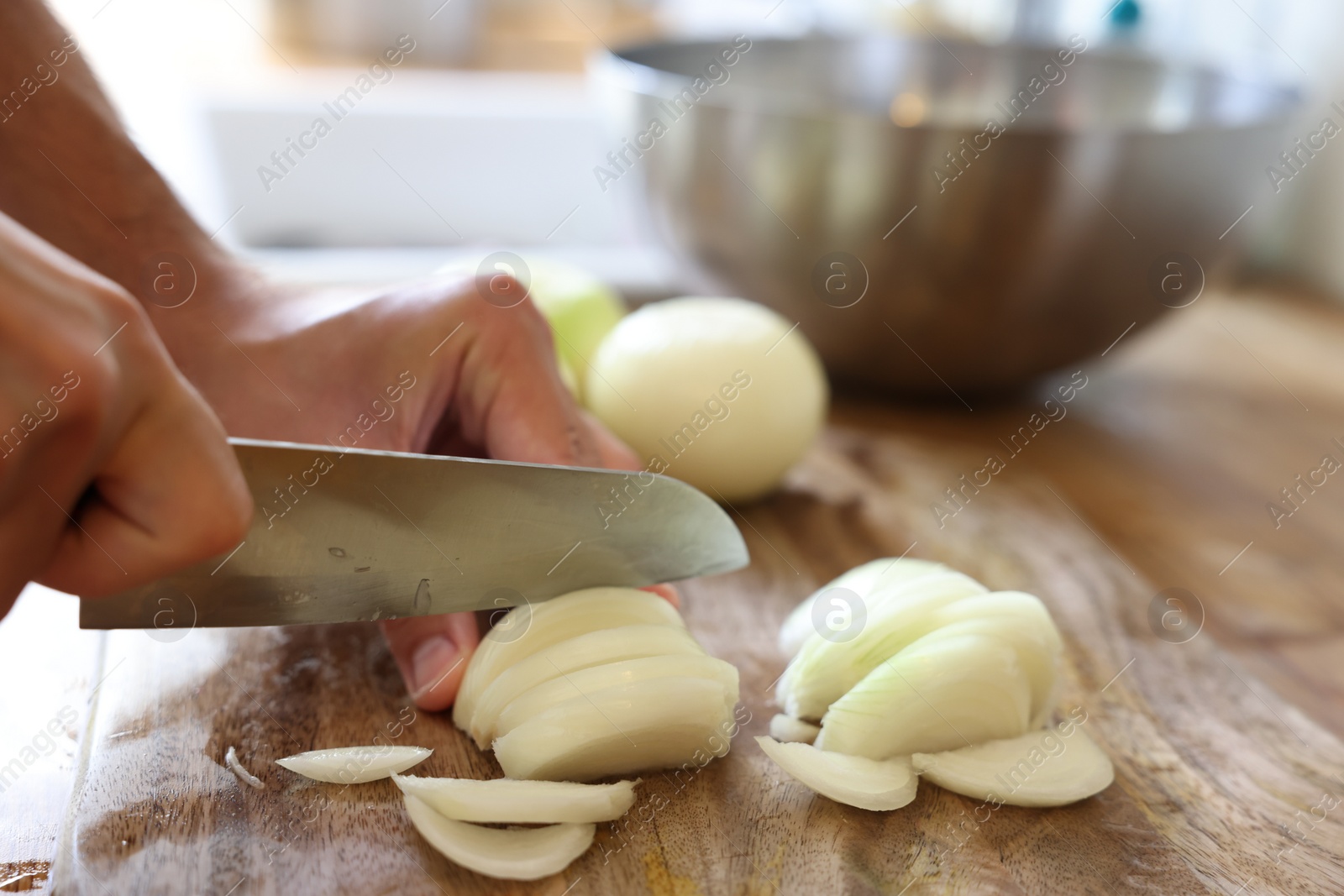 Photo of Woman cutting fresh ripe onion on wooden board, closeup. Space for text