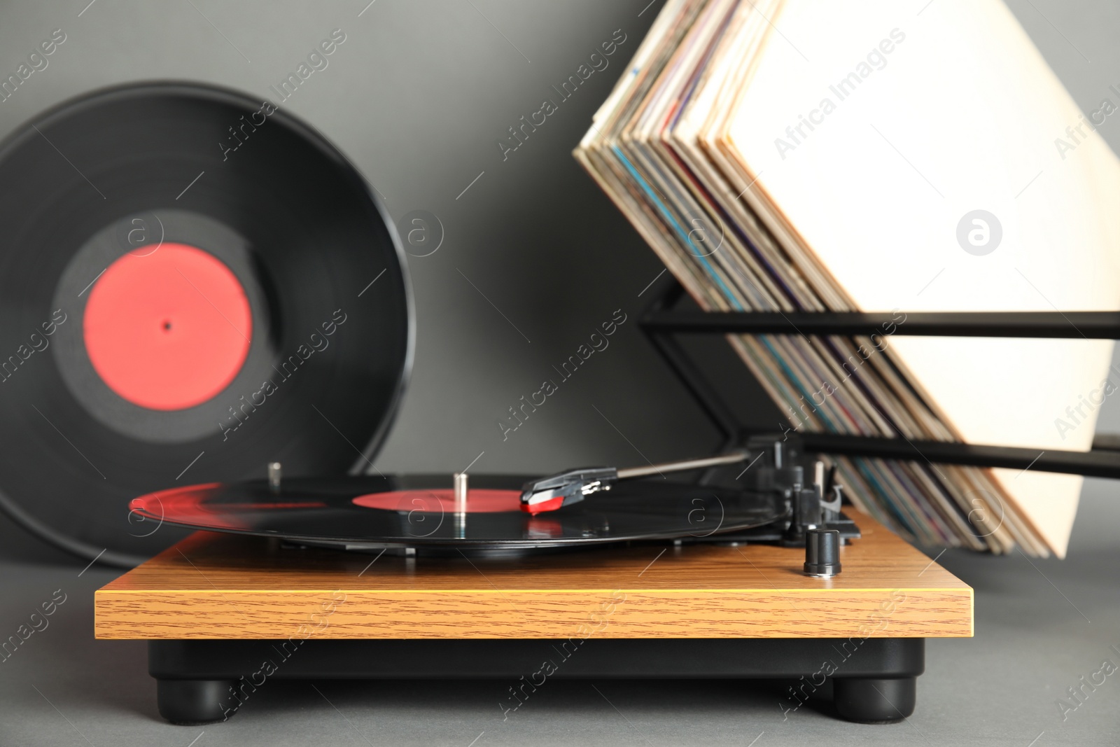 Photo of Modern player and vinyl records on grey background