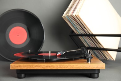 Photo of Modern player and vinyl records on grey background