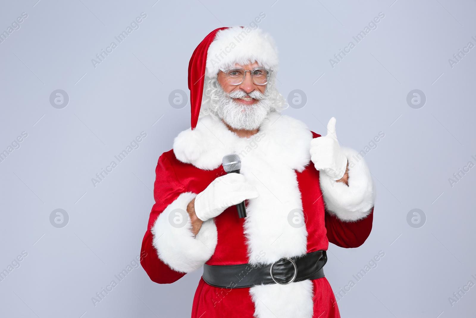 Photo of Santa Claus singing into microphone on color background. Christmas music