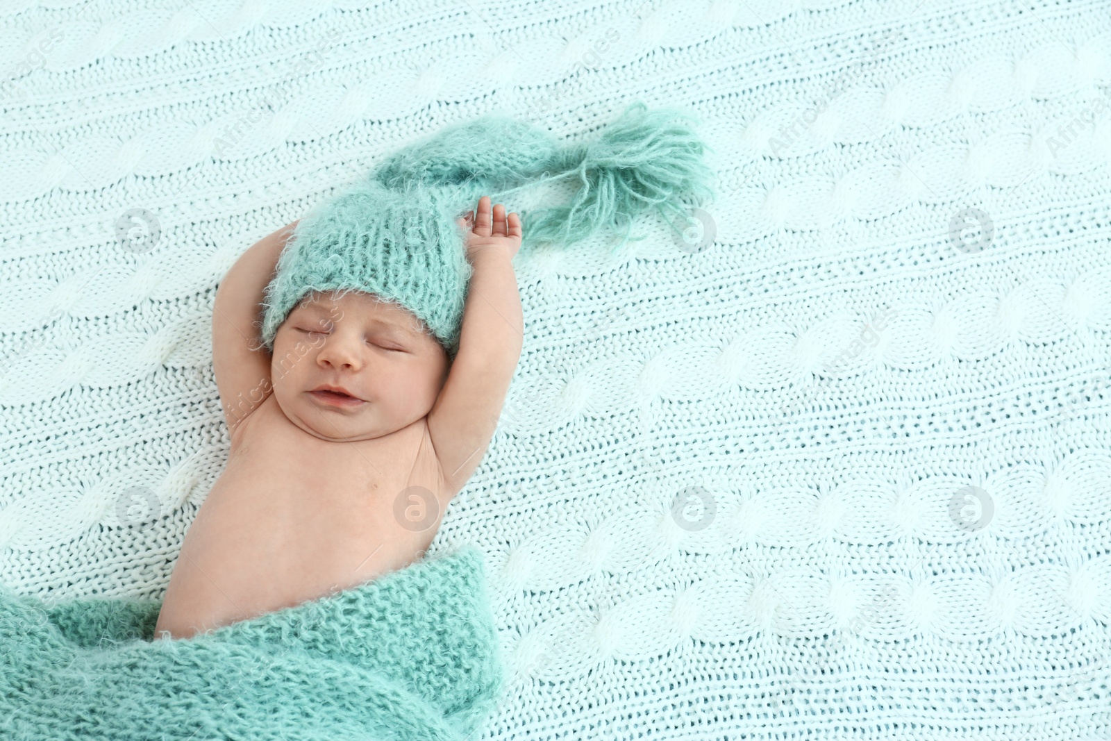 Photo of Cute little baby in green hat lying on soft blanket, top view. Space for text