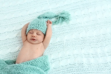 Photo of Cute little baby in green hat lying on soft blanket, top view. Space for text