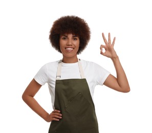 Happy young woman in apron showing ok gesture on white background
